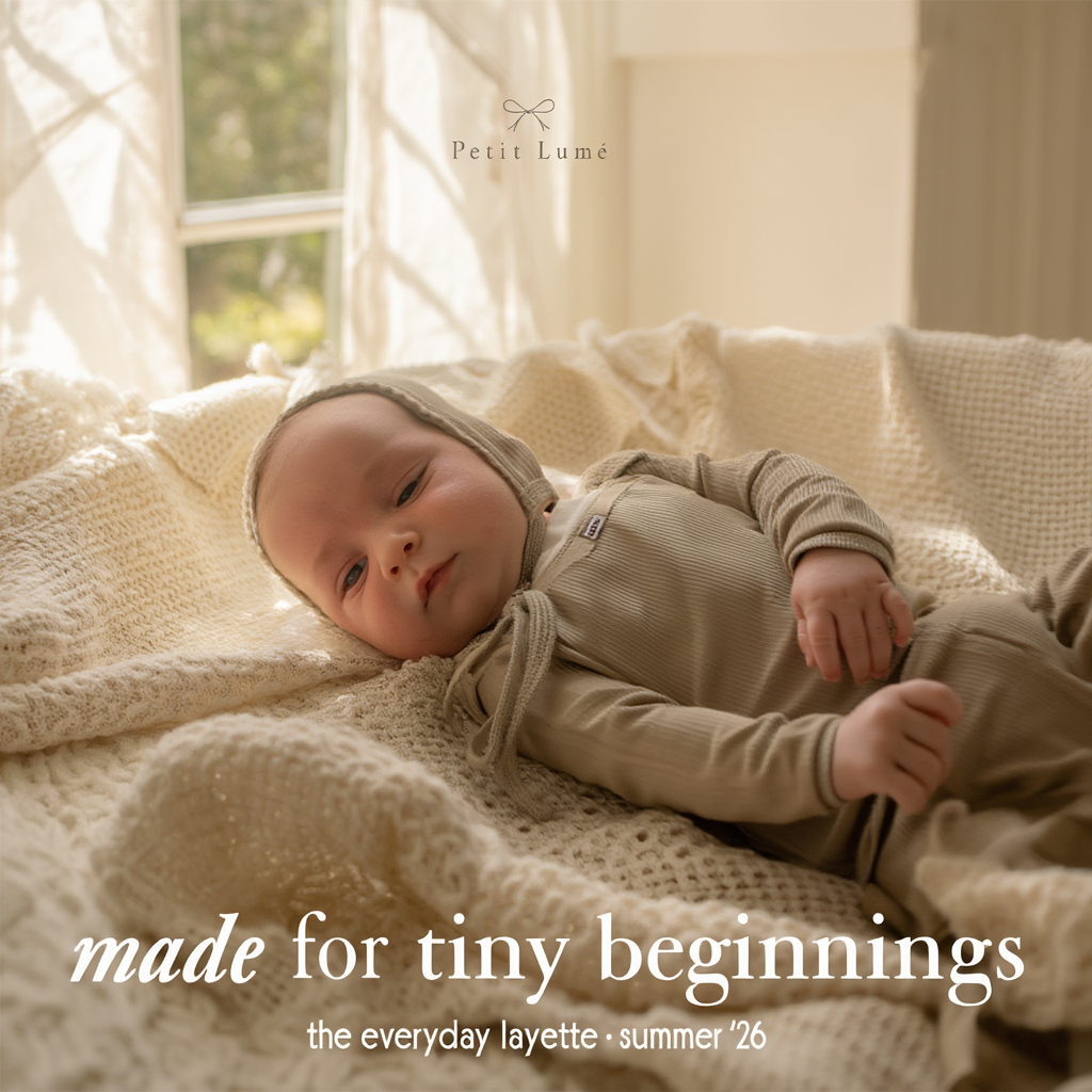 Petit Lu newborn lying on cream knit blankets in a taupe layette set