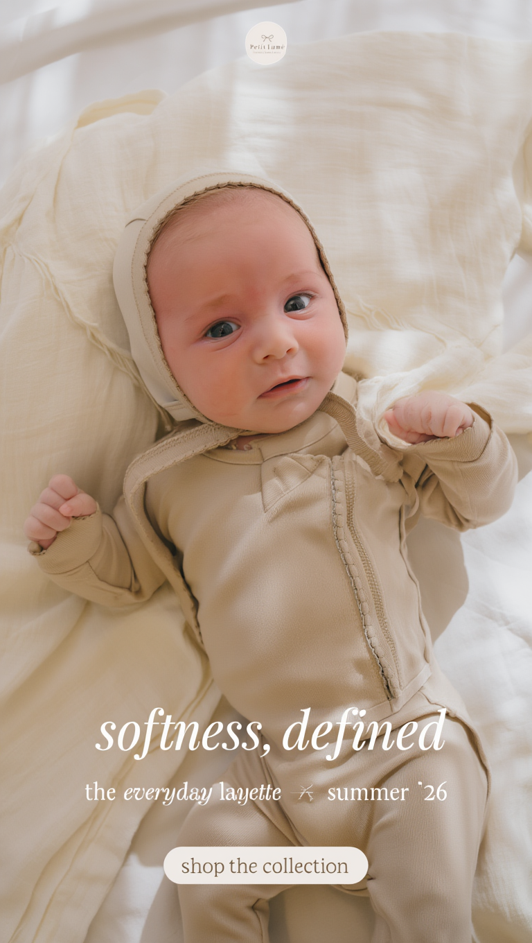 Petit Lu baby in a neutral layette set and bonnet